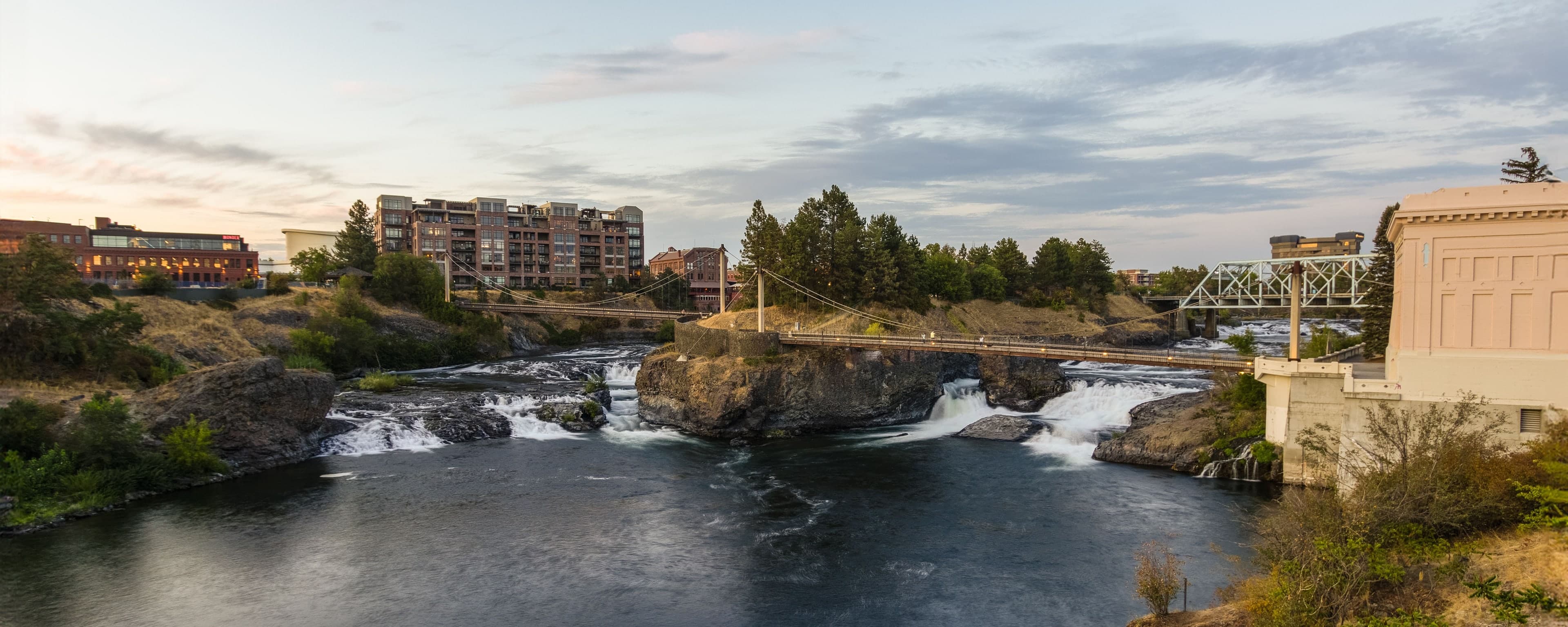 Spokane Falls in downtown Spokane, with a footbridge and city buildings beyond the river